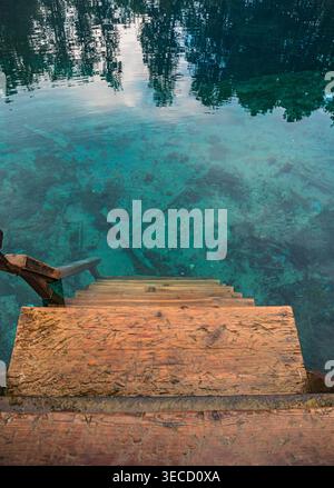 Eine Holztreppe führt in klares türkisfarbenes Wasser. Stockfoto