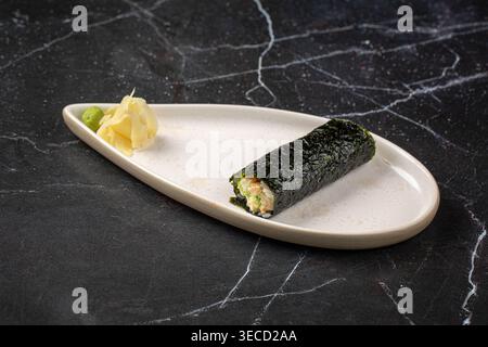 Sushi-Rolle mit Nori auf Teller mit Wasabi Stockfoto