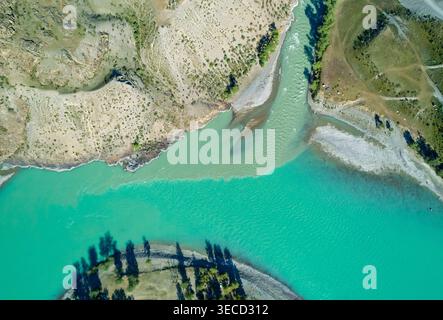 Die Luftaufnahme zeigt den Zusammenfluss des Altai-Flusses mit leuchtendem türkisfarbenem Wasser, das sich mit hellerem grünem Bach in einer riesigen natürlichen Landschaft verschmelzt Stockfoto