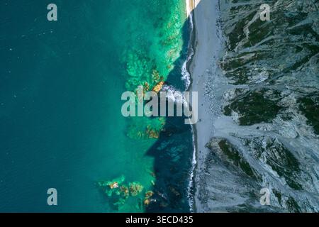 Atemberaubende Aussicht aus der Luft mit klarem türkisfarbenem Meereswasser, einem zerklüfteten felsigen Strand und majestätischen Klippen Stockfoto