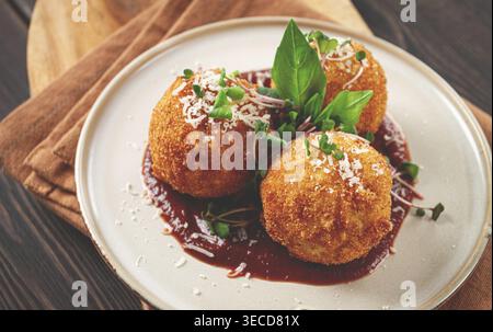 Knusprige Arancini-Vorspeise mit Parmesan und Mikrogrün, Teller, Tomatensauce, hausgemacht, keine Leute Stockfoto