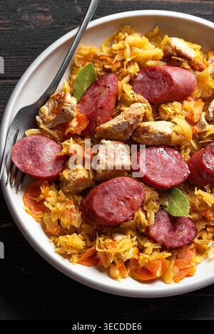 Traditionelle polnische Bigos-Mahlzeit oder Hunter's Stew mit Würstchen, Fleisch und gedünstetem Kohl aus nächster Nähe. Hausgemachtes geschmortes Sauerkraut mit Bratwurst. Stockfoto