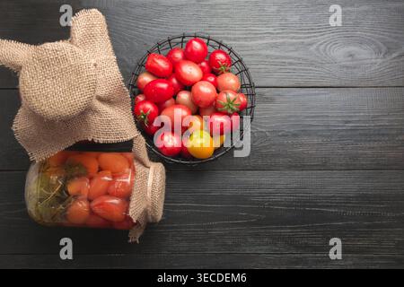 Gemüse-Tomate in Dosen in Glasgläsern auf dunklem Holzbrett. Leerzeichen für Text. Blick von oben. Verschiedene Arten von Dosen. Hausgemachte Erntevorbereitungen im Herbst. Hausaufgaben und Traditionen. Stockfoto