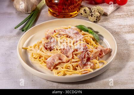 Köstliche Spaghetti Carbonara serviert auf Teller, garniert mit frischem Basilikum. Reichhaltige cremige Sauce, knuspriger Speck und goldene Nudeln sorgen für appetitliche Mahlzeiten Stockfoto