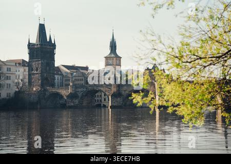 Blick auf historische Gebäude in der Nähe der Karlsbrücke in Prag, sonniger Tag mit Reflexionen im Wasser Stockfoto
