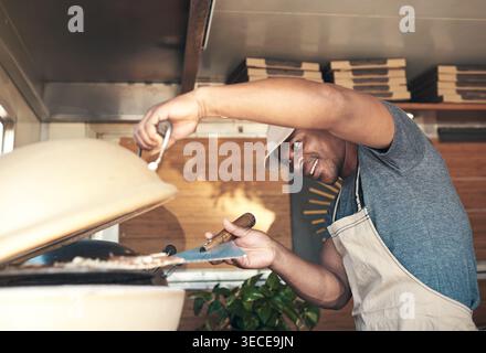Schwarzer Mann, Kochen und Pizza im Ofen im Restaurant für die Zubereitung der Mahlzeiten, Zutaten und italienische Rezepte. Lächeln, Koch und Backprozess für Gebäck Küche Stockfoto