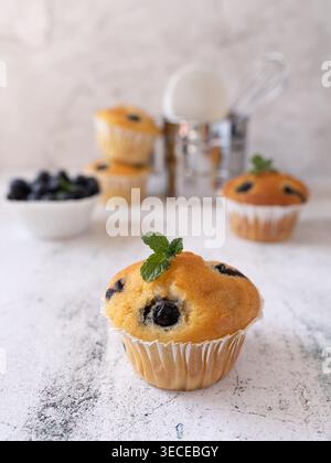 Nahansicht des Heidelbeermuffins mit frischen Beeren und Minze auf weichem, neutralem Hintergrund Stockfoto
