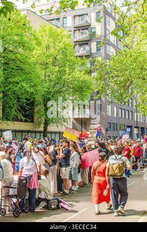Marathonläufer bewegen sich während des London Marathon durch einen schattigen Abschnitt der Jamaica Road, umgeben von Bäumen und Zuschauern. Stockfoto