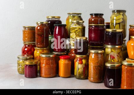 Canning ist eine häufige Aktivität in der Küche, da die Theke mit Gemüse und Obst gefüllte Gläser säumen. Diese Praxis hilft dabei, Lebensmittel für den Gewinn zu bewahren Stockfoto