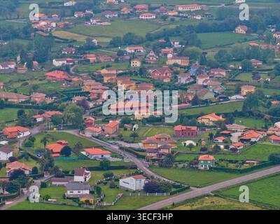 Blick aus der Vogelperspektive auf farbenfrohe Häuser und üppige grüne Gärten im Dorf Cudillero, Asturien, Spanien. Stockfoto