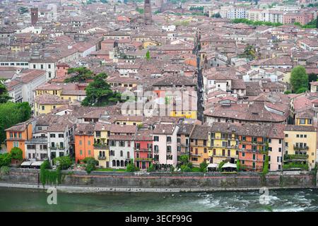 Blick aus der Vogelperspektive auf historische farbenfrohe Gebäude entlang der Etsch mit Terrakotta-Dächern und engen Gassen in Verona, Veneto, Italien. Stockfoto