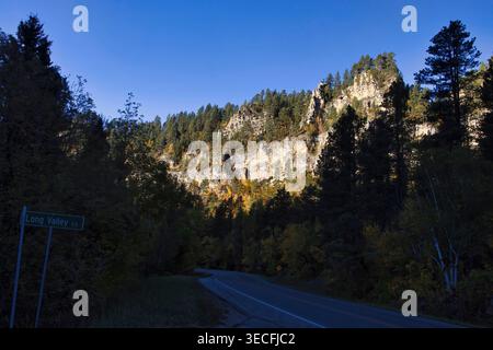 Die Sonne scheint an einem herbstlichen Tag in South Dakota auf den Klippen über der Straße durch den Spearfish Canyon. Stockfoto