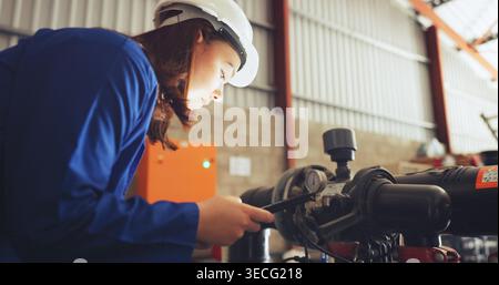 Frau, Techniker und Inspektion mit Tablet im Werk für Systemreparatur, Reparatur oder Wartung. Weibliche Person, Techniker oder Mechaniker, die die Wasserpumpe überprüft Stockfoto