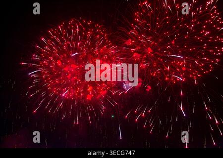 Ein großes rotes Feuerwerk explodiert am Nachthimmel während eines Neujahrsfestes. Feiertagsfeier, Feuerwerk, Nachtpyrotechnik. Weihnachten, Neujahr. Stockfoto