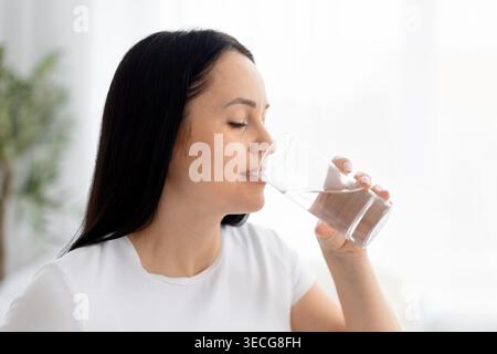 Nahaufnahme-Porträt einer jungen Frau, die mit geschlossenen Augen ein Glas Wasser trinkt Stockfoto