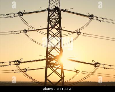 Aus der Vogelperspektive eines Hochspannungs-Pylons vor dem goldenen Sonnenuntergang mit Stromleitungen, die sich über den Horizont Armthorpe, Englan, erstrecken Stockfoto