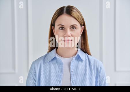 Nahporträt einer professionellen jungen Frau, die vor weißem Hintergrund in die Kamera blickt Stockfoto