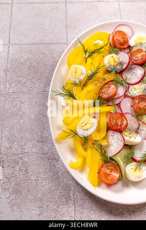 Lebendiger Salat mit gelben Paprika, roten Radieschen, Kirschtomaten, Gurken, Dill, und hart gekochte Wachteleier, die ein nahrhaftes erzeugen Stockfoto