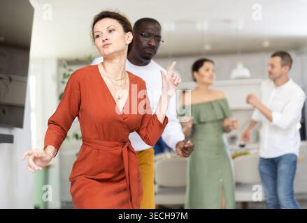 Fröhliche Frau, die aktiv tanzen kann, wenn sie sich zu Hause versammelt Stockfoto