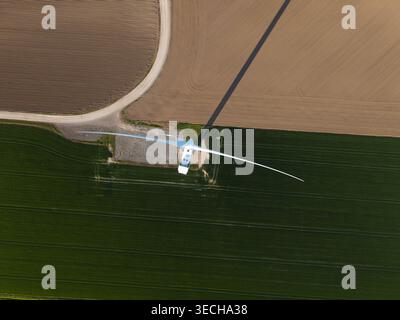 Luftaufnahme der Keadby Wind Farm mit einer einzigen Windturbine, die einen langen Schatten über grüne und braune landwirtschaftliche Felder in Keadby, England, Uni wirft Stockfoto