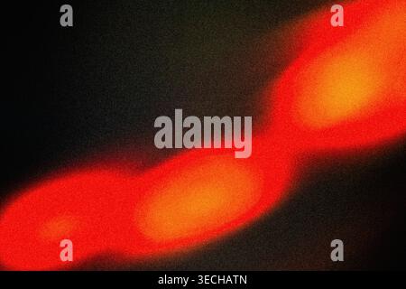 Abstrakter Hintergrund mit körniger Textur und verschwommenen roten orangefarbenen hellen Flecken auf Dunkelheit Stockfoto