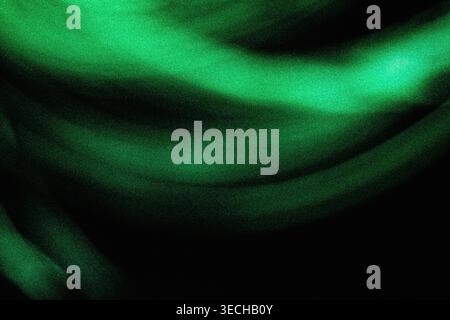 Wellige, hellgrüne leuchtende Bänder mit einer körnigen Textur gegen dunkle Räume Stockfoto
