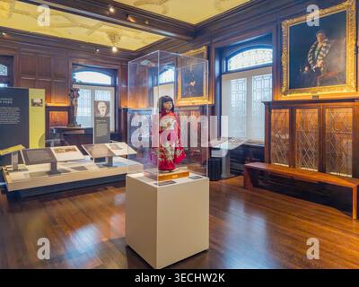 Kansas, USA, 18. JAN 2026 - Eine bunte Puppe mit rotem Kimono steht in einem Glaskasten in einem großen Museumsraum mit Holzpasta Stockfoto