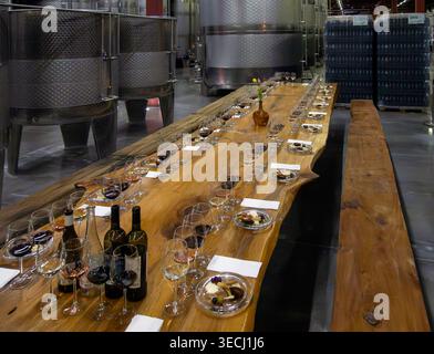 Langer Holztisch, der zur Vorbereitung einer Weinprobe im Keller eines Weinguts aufgestellt wurde Stockfoto