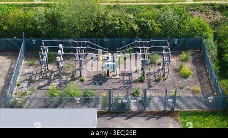 Aus der Vogelperspektive eines elektrischen Umspannwerks mit Transformatoren und Stromleitungen, umgeben von einem Metallzaun, umgeben von grünen Bäumen in Hampole, England, Uni Stockfoto