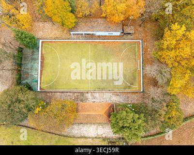 Aus der Vogelperspektive auf das Fußballfeld von Praia Fluvial de Alvoco das Varzeas umgeben von lebhaften Herbstbäumen mit gelbem Laub in Alvoco das Varzeas, C Stockfoto