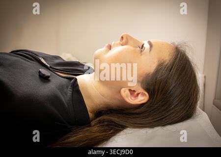 Ein Bild einer sehr schönen und attraktiven jungen Dame, die den Prozess der Lippeninjektion und Verjüngung zeigt, in einem professionell gestalteten Büro Stockfoto