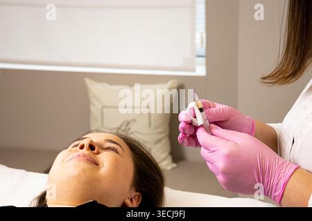 Ein Bild einer sehr schönen und attraktiven jungen Dame, die den Prozess der Lippeninjektion und Verjüngung zeigt, in einem professionell gestalteten Büro. Dies Stockfoto