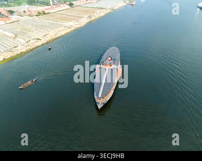 Aus der Vogelperspektive einer großen Passagierfähre, die auf dem Buriganga River in der Nähe von Sadarghat mit kleinen Holzbooten und Industriebanken in Dhaka, Dhaka Div, fährt Stockfoto