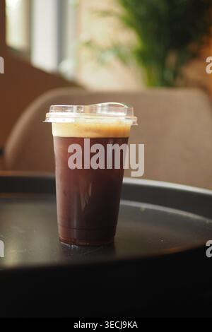 Kalter Kaffee, serviert in Plastikbecher auf einem Tisch Stockfoto
