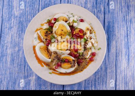 Eierschale mit Gewürzen und Granatapfel auf einem blauen Tisch Stockfoto