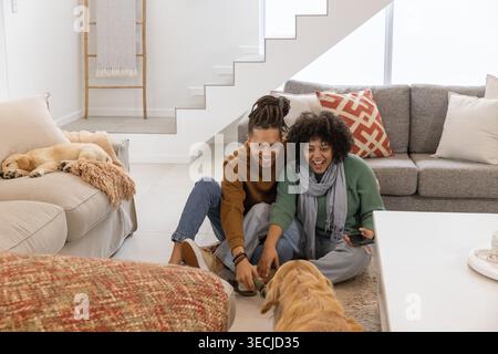 Legenes Paar in Pullover, das sich im Wohnzimmer, Telefon und schlafender Hund zum Hund wendet Stockfoto