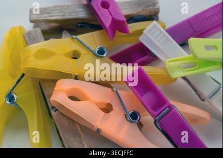 Helle Nahaufnahme farbenfroher Wäscheständer und Wäschestifte aus Kunststoff und Holz, die Texturen, Metallfedern und alltägliche Haushaltswäscherei hervorheben Stockfoto