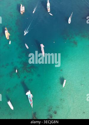Blick aus der Vogelperspektive auf verschiedene Boote und Yachten, die im türkisfarbenen tropischen Wasser des Hafens Labuan Bajo, East Nusa Tenggara, Indonesien, ankern. Stockfoto