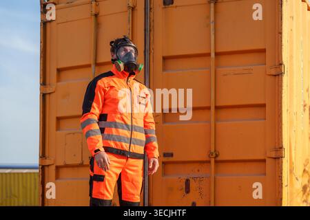 Kaukasischer Arbeiter im mittleren Erwachsenenalter stellt eine Atemschutzmaske durch den Versand von Behältern für Sicherheitsschulungen, Arbeitsschutz und giftige Umgebungen ein Stockfoto