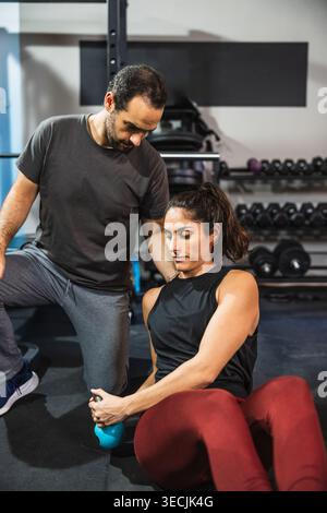 Personal Trainer führt Frau durch funktionelles Trainingstraining Stockfoto