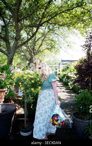 Frau mit Blumenstrauß im sonnigen Fairhope Gartencenter Stockfoto