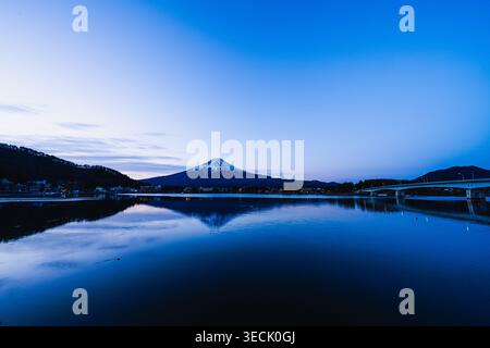 Atemberaubende Sonnenaufgangsspiegelung des schneebedeckten Mount Fuji auf dem ruhigen Wasser des Kawaguchiko-Sees in Yamanashi, Japan Stockfoto