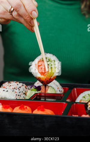Mädchen isst asiatisches Essen aus der bento-Box mit Essstäbchen Stockfoto