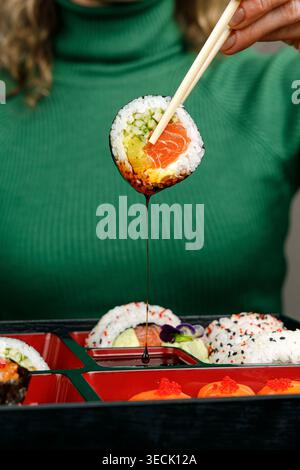 Mädchen isst asiatisches Essen aus der bento-Box mit Essstäbchen Stockfoto