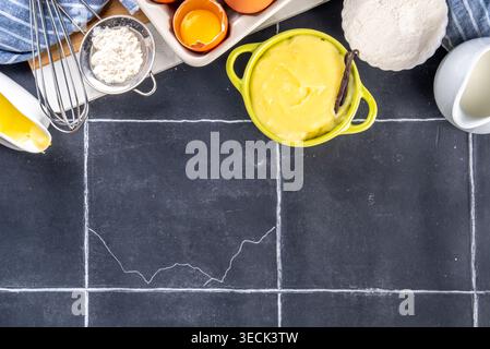 Hausgemachte Creme mit Zutaten - Vanille, Milch und Eier. Süße Creme anglaise Dessertkoch Hintergrund, auf schwarzem Küchentisch Kopierraum Stockfoto