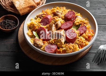 Traditionelle polnische Bigos-Mahlzeit oder Hunter's Stew mit Würstchen, Fleisch und gedünstetem Kohl aus nächster Nähe. Hausgemachtes geschmortes Sauerkraut mit Bratwurst. Stockfoto