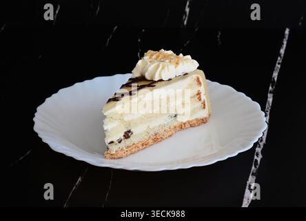 Ein Stück Kuchen auf einer weißen Platte vor dunklem Hintergrund Stockfoto