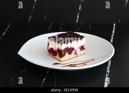 Donauwellenkuchen auf weißem Teller vor dunklem Hintergrund Stockfoto