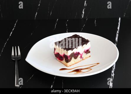 Donauwellenkuchen auf weißem Teller vor dunklem Hintergrund Stockfoto