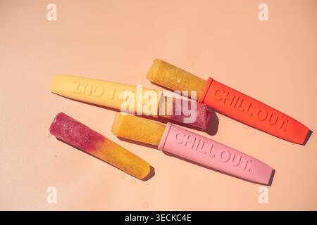 Farbenfrohe hausgemachte Fruchteis-Eis-Eis-Eis-Eis in Silikonformen auf pastellfarbenem Hintergrund, in flacher Lage gestylt. Erfrischendes Dessert-Konzept für die Sommerhitze Stockfoto